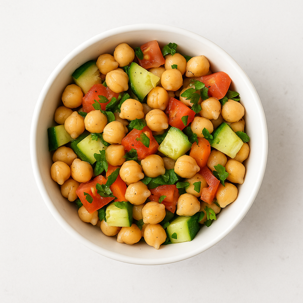 ensalada de garbanzos templada con verduras salteadas servida en plato blanco, receta saludable y mediterránea