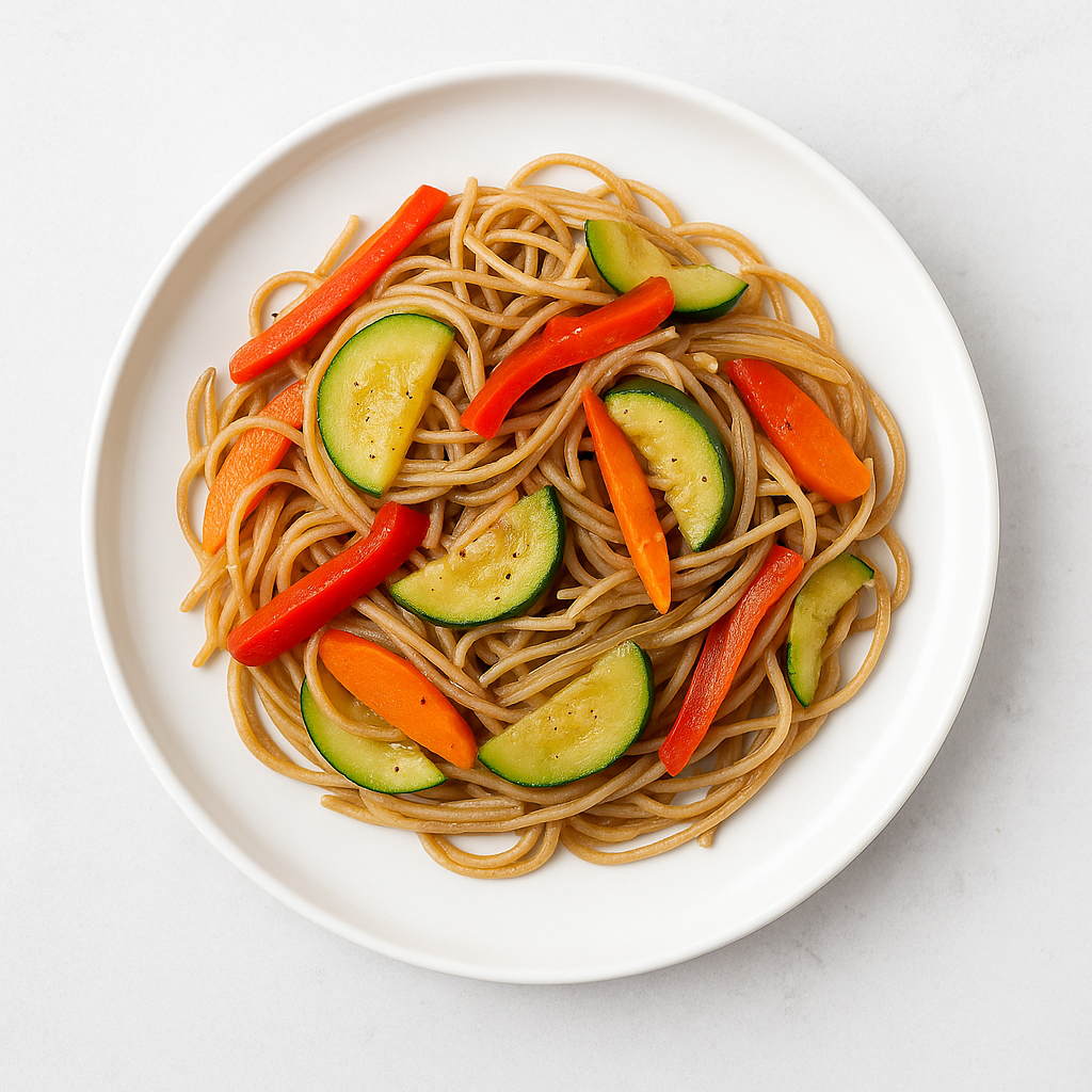 espaguetis integrales con verduras salteadas servidos en plato blanco, receta saludable y mediterránea